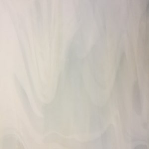 May include: White fabric with a smooth, flowing texture. The fabric is draped and folded, creating soft, rounded shapes.