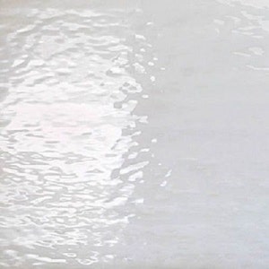 May include: A close-up view of a white, glossy surface with a rippled texture. The light reflects off the surface, creating highlights and shadows that mimic the appearance of water. The overall effect is a sense of fluidity and movement.