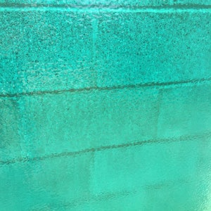 May include: A close-up of a turquoise blue textured surface with horizontal lines. The surface has a slightly iridescent sheen.