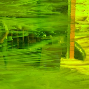 May include: Abstract green and yellow glass with a swirled pattern. The glass has a translucent quality and appears to be made of multiple layers.