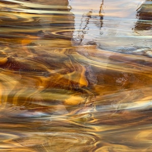 May include: Abstract art featuring swirling patterns of brown, gold, and white. The colors are reminiscent of water and create a sense of movement.