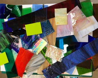 May include: Assortment of colorful glass pieces in various shapes and sizes. The glass pieces are arranged on a white surface. The glass pieces are perfect for stained glass projects.