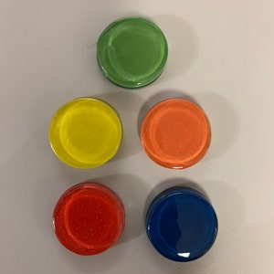 May include: Five round glass tiles in different colors. The tiles are green, yellow, orange, red, and blue. The tiles are arranged in a pyramid shape.