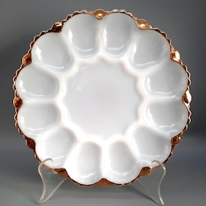 May include: White milk glass egg plate with a gold rim. The plate has 10 individual indentations for serving eggs.