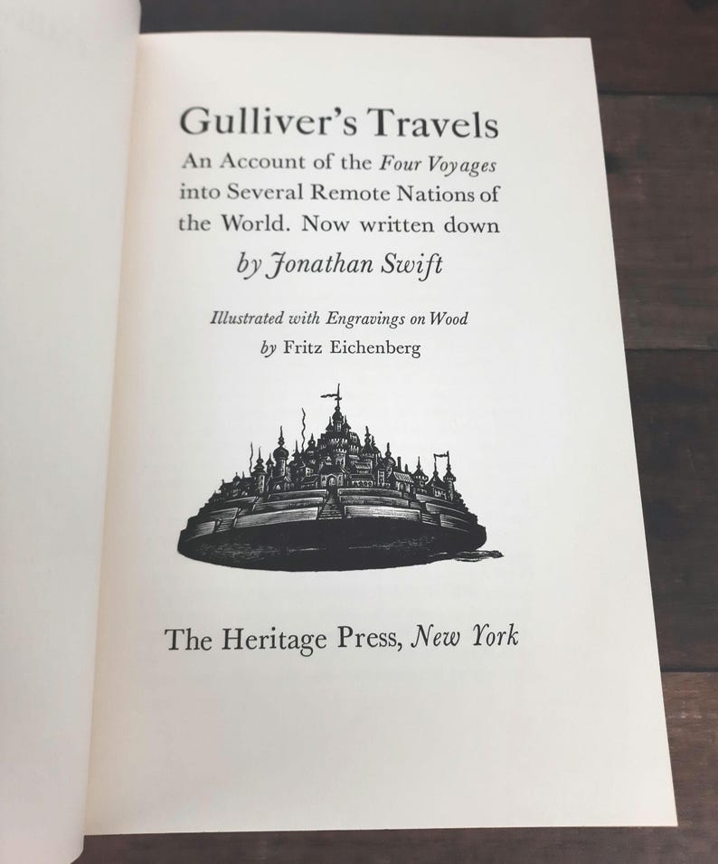 K&ouml;nnte beinhalten: Offenes Buch mit dem Titel "Gulliver's Travels" und Text von Jonathan Swift. Das Buch zeigt eine Illustration einer Stadt und wird von The Heritage Press, New York, herausgegeben.