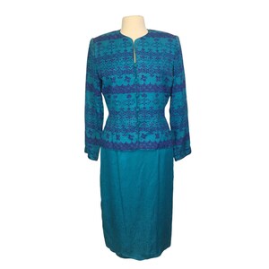 May include: A teal blue skirt suit with a patterned jacket. The jacket has a blue and purple floral pattern. The skirt is solid teal blue.