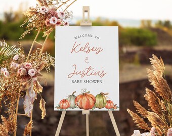 May include: Welcome to Kelsey & Justin's Baby Shower sign with a watercolor illustration of pumpkins. The sign is on a wooden easel.