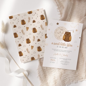 May include: A baby shower invitation with a brown owl and Libra zodiac symbol. The invitation is decorated with gold stars and a white background. The text reads "a sweet little libra is on the way".
