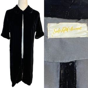 May include: A black velvet jacket with a collar and short sleeves. The jacket has a label that reads "Saks Fifth Avenue".