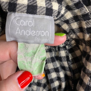 May include: A black and white gingham fabric with a white tag that says "Carol Anderson Petite" in black text.