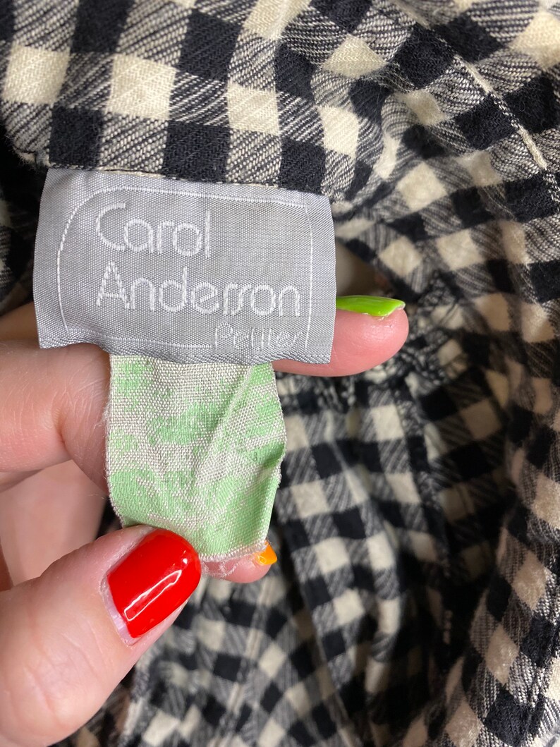 May include: A black and white gingham fabric with a white tag that says "Carol Anderson Petite" in black text.