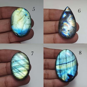May include: Four labradorite gemstone cabochons in various shapes and sizes. The stones are a mix of blue, green, and gold colors with iridescent flashes.