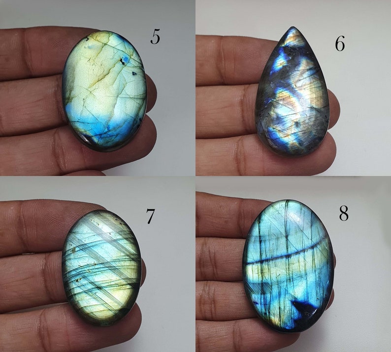 May include: Four labradorite gemstone cabochons in various shapes and sizes. The stones are a mix of blue, green, and gold colors with iridescent flashes.
