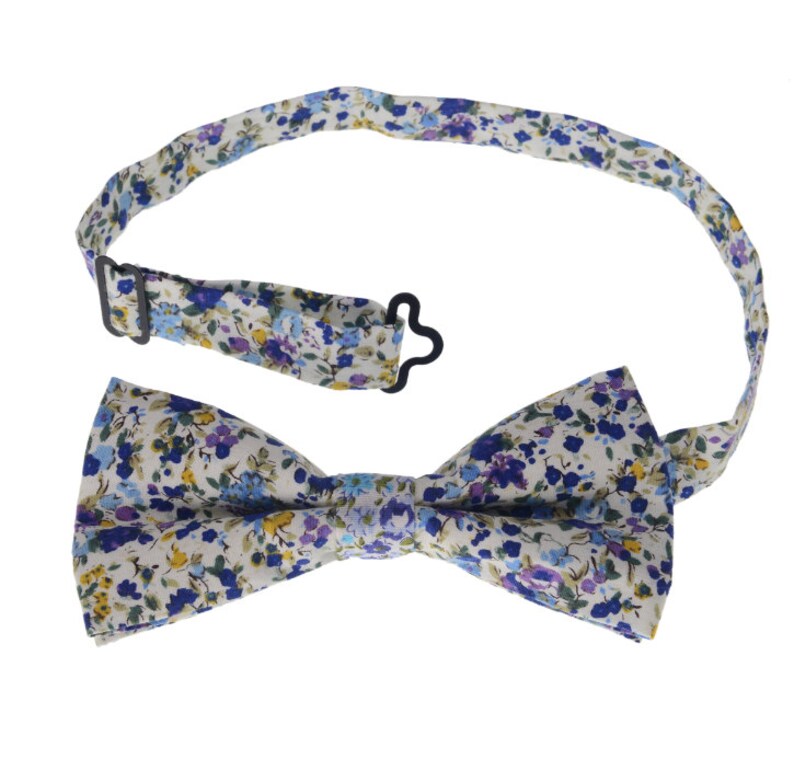 May include: A white bow tie with a blue and purple floral pattern. The bow tie has an adjustable strap with a metal clasp.