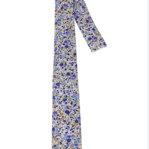 May include: A white tie with a blue and yellow floral pattern. The tie is made of a soft, comfortable fabric and is perfect for adding a touch of style to any outfit.