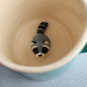 Surprise mug turquoise green ceramic coffee cup with black and grey raccoon - racoon animal figurine miniature