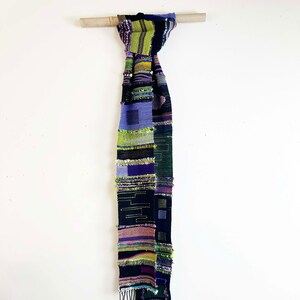 Handwoven Scarf in Black Cotton and Assorted Fibers in Greens and Purples.