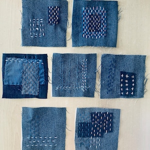 Könnte beinhalten: Neun blaue Jeansquadrate mit verschiedenen weißen Steppmustern. Die Quadrate sind in drei Reihen zu je drei angeordnet.