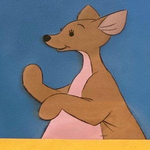 Puede incluir: Un canguro de dibujos animados marr&oacute;n con detalles rosas y orejas grandes, de pie sobre un fondo azul.