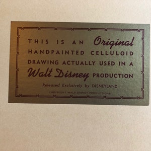 Puede incluir: Una etiqueta dorada con un borde burdeos y un texto que dice "THIS IS AN Original HANDPAINTED CELLULOID DRAWING ACTUALLY USED IN A Walt Disney PRODUCTION Released Exclusively by DISNEYLAND COPYRIGHT WALT DISNEY PRODUCTIONS".