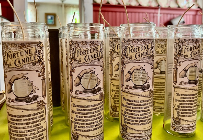 May include: A row of clear glass fortune candles with a vintage design. Each candle features a hand holding a crystal ball and the text "Fortune Candle".