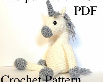 May include: A crocheted white unicorn with a gray horn and mane. The unicorn is sitting with its legs crossed. The text "The perfect unicorn PDF Crochet Pattern, instant download in US" is below the unicorn.