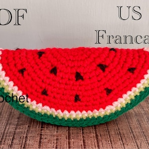 Op de afbeelding: Een gehaakte watermeloen schijf met een rood midden, zwarte zaaddetails en groene schil. De rand heeft witte en gele accenten. Het woord "Crochet" is zichtbaar.
