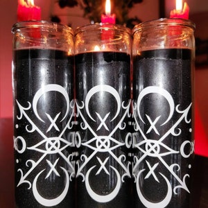 May include: Three black glass candle jars with white decorative designs and red candle wicks. The candles are lit and the flames are visible.