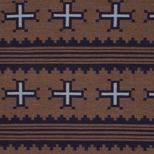 May include: Brown fabric with a repeating pattern of white crosses and dark blue geometric shapes. The design includes horizontal lines and a textured appearance, creating a visually appealing textile.