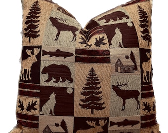 May include: A brown and beige throw pillow with a patchwork design featuring various woodland creatures, including moose, deer, bears, and fish. The pillow has a rustic and outdoorsy theme.