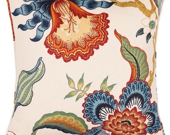 May include: A white throw pillow with a floral pattern in shades of red, orange, blue, and green. The pillow features a large, stylized flower in the center, surrounded by smaller flowers and leaves.
