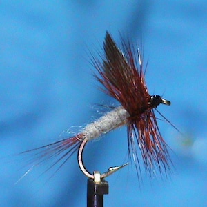 May include: A brown and gray fly fishing lure with a black head and a silver hook.
