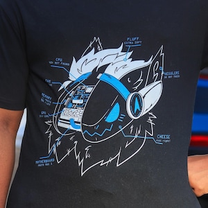 May include: Black t-shirt featuring a detailed diagram of a stylized robotic animal head. The design includes text labels like "CPU," "Memory," and "Fluff." The graphic is rendered in white and blue, creating a striking contrast against the black fabric.