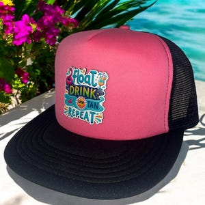 May include: Pink and black trucker hat with a colorful graphic that says "Float, Drink, Tan, Repeat".