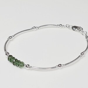 Peut inclure: Un bracelet en argent d&eacute;licat avec de petites perles rondes et cinq pierres pr&eacute;cieuses vertes &agrave; facettes. Le bracelet a un design simple et &eacute;l&eacute;gant avec un fermoir s&eacute;curis&eacute;.