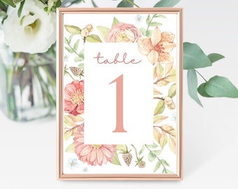 May include: A floral table number card with a peach background and a white border. The card has a peach floral design and the text "table 1" in a peach font.