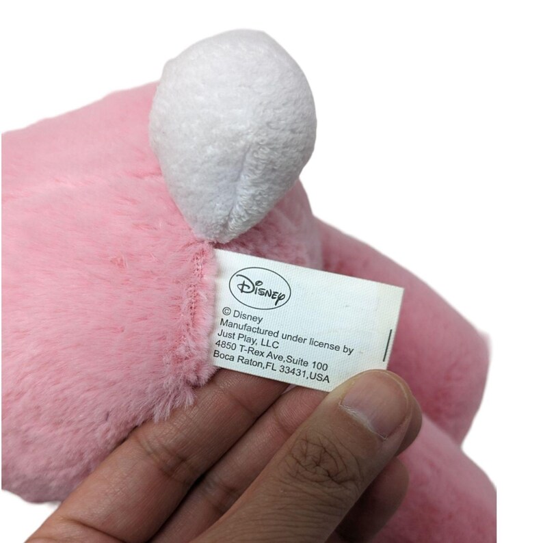 May include: Pink plush toy with a white head and a Disney tag that reads: &copy;Disney Manufactured under license by Just Play, LLC 4850 T-Rex Ave, Suite 100 Boca Raton, FL 33431,USA