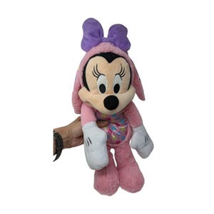 May include: Pink plush Minnie Mouse toy with a purple bow and a colorful polka dot pattern on her dress.