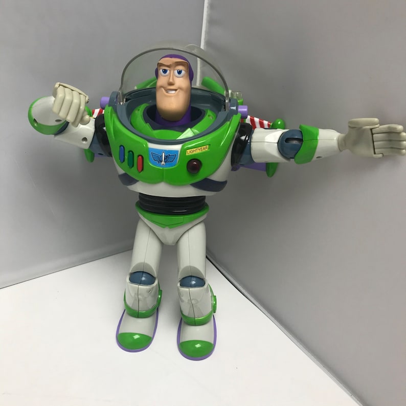 May include: A green and white Buzz Lightyear action figure with a purple helmet and a red button that says "LIGHTYEAR".