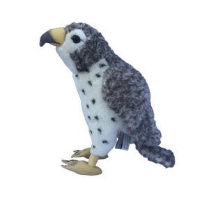 Puede incluir: Un peluche de pájaro con cuerpo blanco salpicado de manchas negras y alas grises. El pájaro tiene pico y patas amarillas y ojos negros. El juguete está diseñado para parecerse a un ave rapaz.