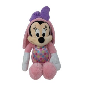 May include: Pink plush Minnie Mouse dressed as an Easter bunny with a purple bow. She has a pink and white polka dot dress and white gloves.