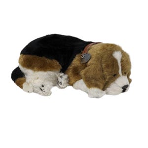 Könnte beinhalten: Ein Stofftier in Form eines Beagle-Hundes in Ruheposition. Das Spielzeug hat ein Farbschema aus Schwarz, Braun und Weiß, mit einem braunen Lederhalsband und einem herzförmigen Anhänger. Das Fell des Hundes ist weich und strukturiert.