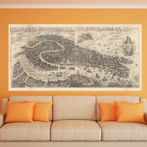 Puede incluir: Un mapa antiguo de Venecia, Italia, cuelga sobre un sofá beige con cojines naranjas. El mapa presenta ilustraciones detalladas de la ciudad. La habitación tiene paredes naranjas, una mesa auxiliar con un jarrón y una lámpara de pie con una pantalla naranja.