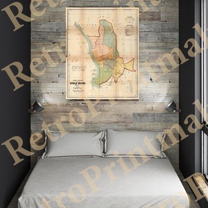 May include: A vintage map of Tepic, Mexico, printed on aged paper, with a light brown background and colorful markings. The map is framed and hanging on a wood-paneled wall above a bed with white linens.