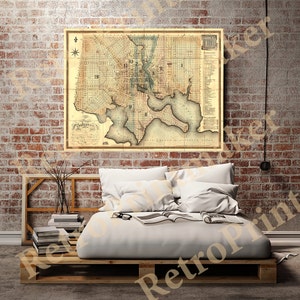 May include: An antique map of Baltimore, Maryland, printed on aged paper with a light brown background. The map shows the city's streets, waterways, and landmarks. The map is framed and hanging on a brick wall.