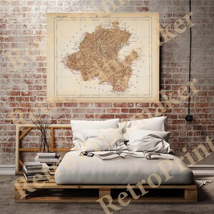 May include: A vintage map of the island of  'Nijalko' with a brown and beige color scheme. The map is framed and hanging on a brick wall above a bed with white bedding.