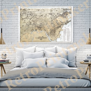 May include: A vintage map of Cambridge, Massachusetts, printed in black and white, framed and hanging on a white brick wall above a bed with white bedding and pillows.