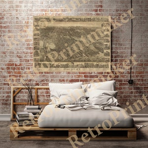 May include: A vintage map of Jersey City, New Jersey, printed in black and white on cream-coloured paper. The map is framed and hanging on a brick wall above a white bed with white pillows and a book on top of it.