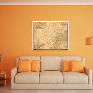Könnte beinhalten: Ein beiges Sofa mit zwei orangefarbenen Kissen in einem Wohnzimmer mit einer orangefarbenen Wand, einem Vintage-Kartenbild an der Wand und einer Stehlampe mit einem braunen Lampenschirm.