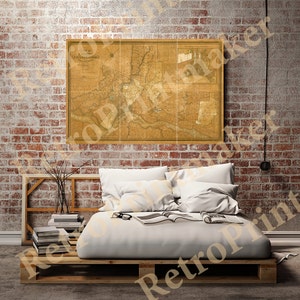 May include: A vintage map of Philadelphia, Pennsylvania, printed on paper with a yellowed, aged appearance. The map is framed and hanging on a brick wall above a bed with white bedding and pillows.